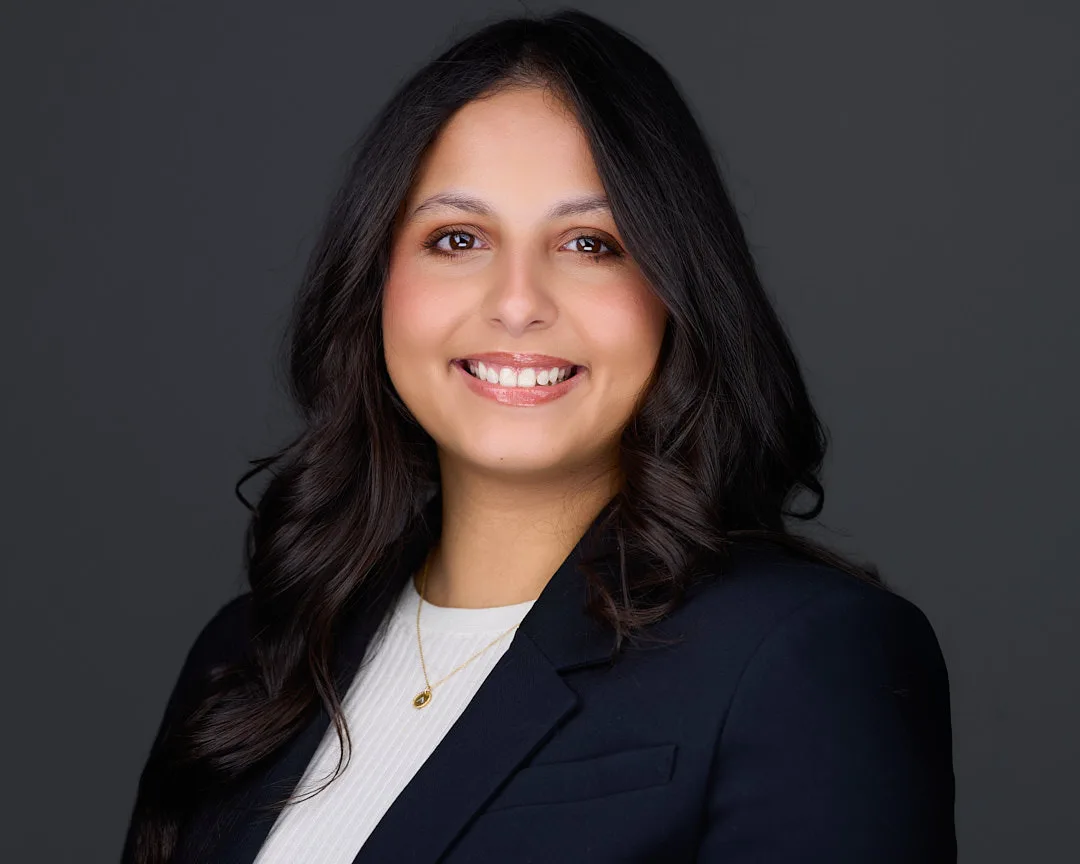Professional headshot of a smiling Reston VA professional in a navy blazer with a gold necklace