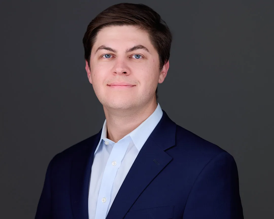 Professional headshot of a Loudoun County professional in a navy blazer and light blue shirt on a gray studio backdrop