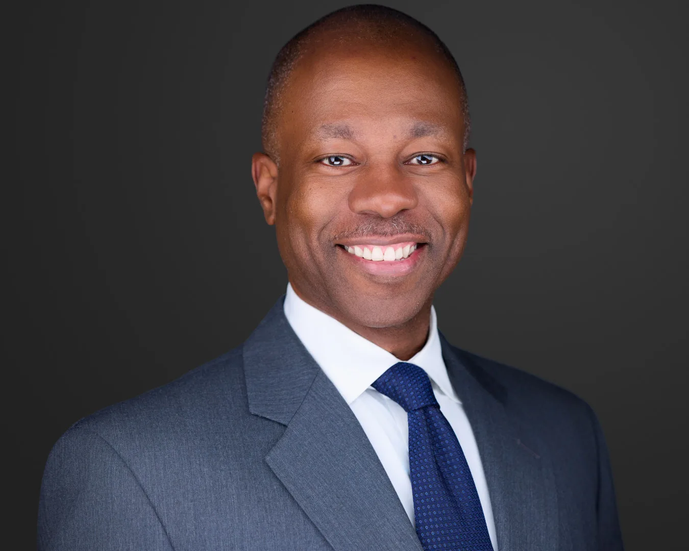 Professional studio headshot of a man in a gray suit showing sculpted key lighting and a smooth background gradient