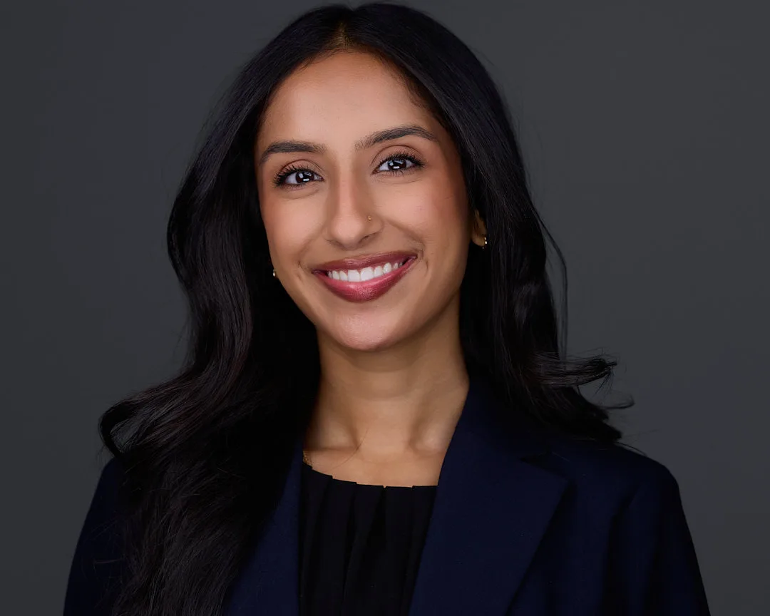 Professional headshot with confident expression against studio backdrop