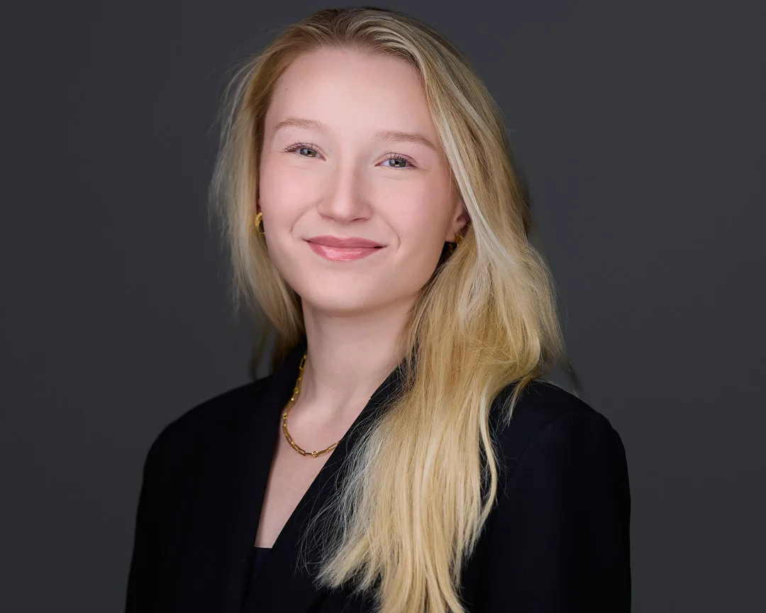 LinkedIn headshot with warm approachable smile and professional styling against studio background